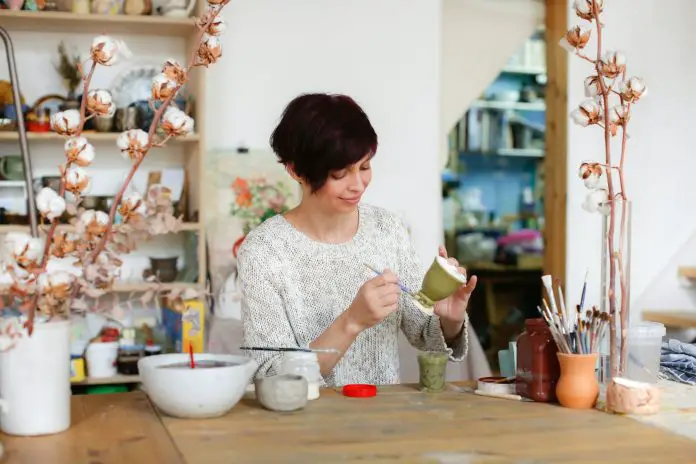 Pretty Caucasian woman painted ceramic bowl in crafting room