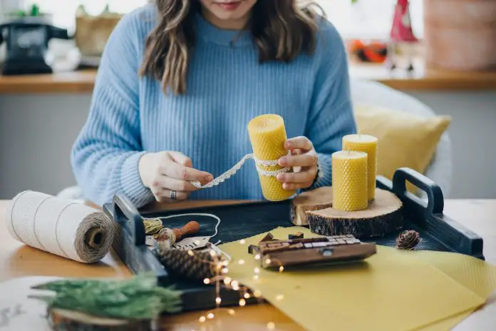 Woman making craft handmade candles at home in winter holidays season.
